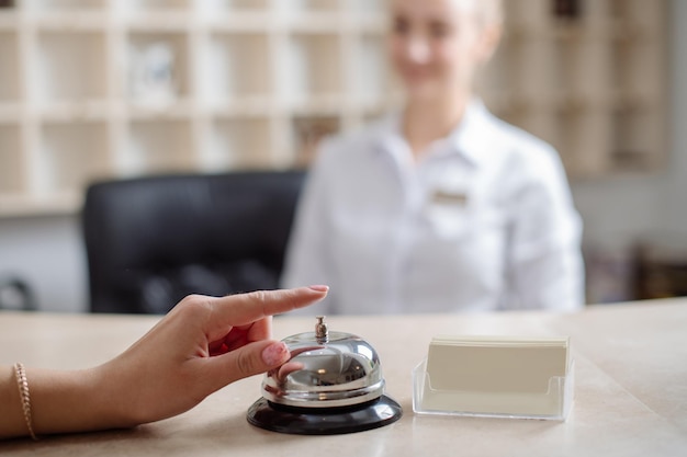 A guest in the hotel is ringing on the bell on the reception