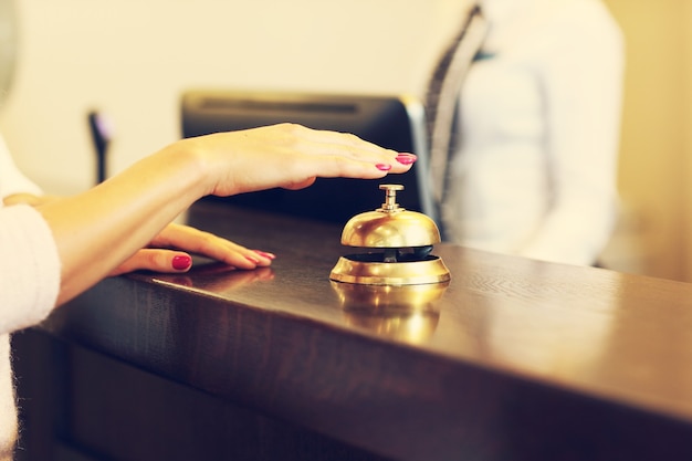 Photo guest using bell at reception desk in hotel