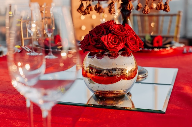 Guests table setting for banquet in black red and gold style Decor  vase with roses on mirror