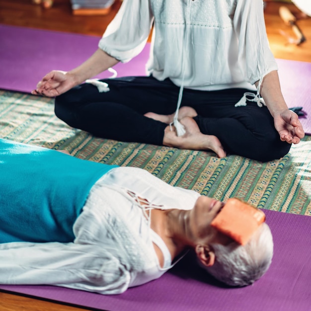 Photo guided meditation senior woman and mid adult woman lying on the floor and meditating
