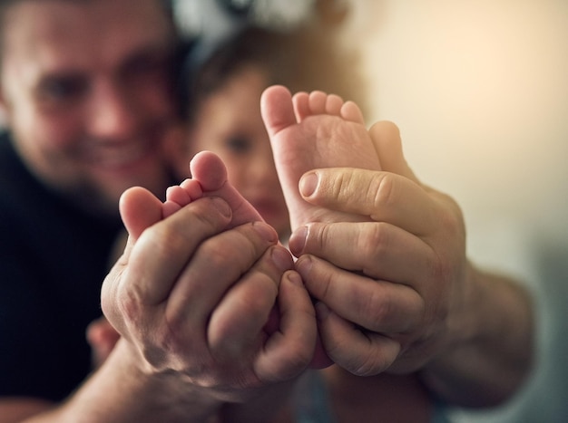 Guiding her footsteps Closeup shot of a mans hands holding his daughters feet