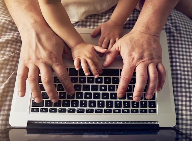 Guiding her hands High angle shot of an unrecognizable father and daughter playing on a laptop