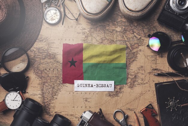 Guinea-Bissau Flag Between Traveler's Accessories on Old Vintage Map. Overhead Shot
