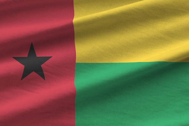 Photo guinea bissau flag with big folds waving close up under the studio light indoors the official symbols and colors in banner