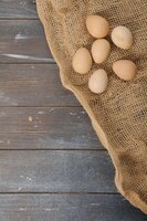 Photo guinea fowl eggs located on burlap on wooden dyed background