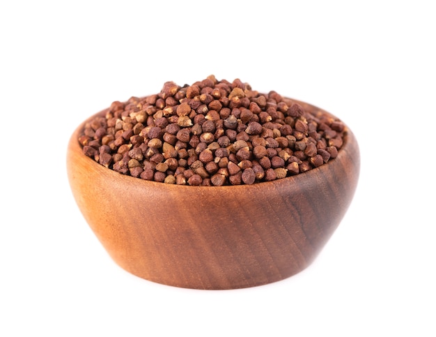 Guinea pepper grains in wooden bowl, isolated  