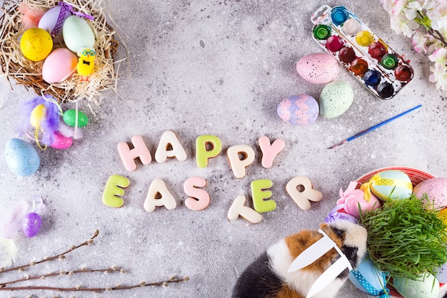 Guinea pig with the ears of the Easter bunny on the stone background of colored eggs