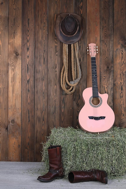 Foto chitarra e stivali da cowboy nel fienile