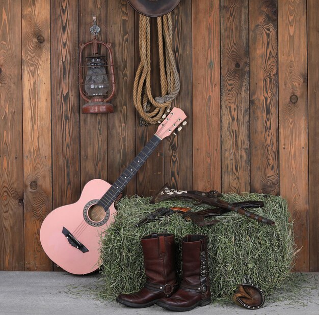 guitar cowboy boots and gun on a wooden floo