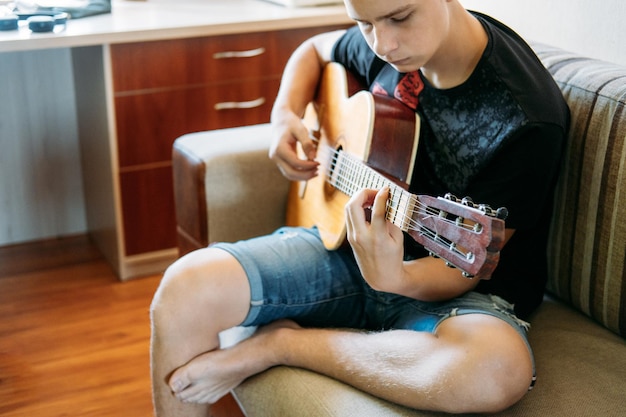 Guitar lessons for beginners caucasian teenager playing guitar having online guitar lessons enjoying