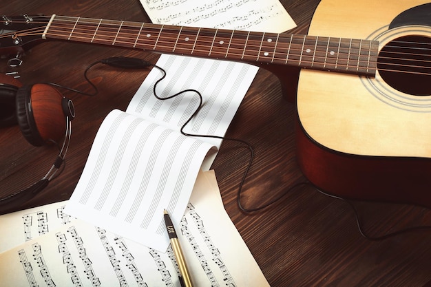 Guitar and music sheets on wooden background
