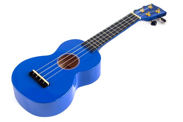 Фото Музыкальный инструмент гитары синим цветом на белом фоне. укулеле. изолировать. скопируйте пространство.