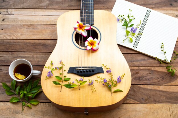 Guitar, notebook and hot coffee on wooden table