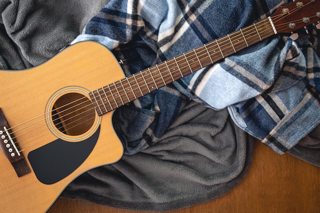 Guitar and plaids on a wooden background top view