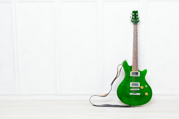 Guitar propped in front of a white wall background