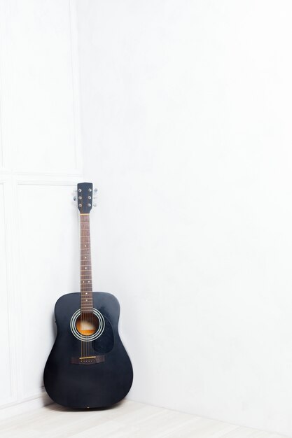 Guitar propped in front of a white wall 