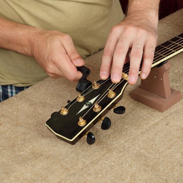 Foto riparazione e servizio di chitarra l'operaio ripara una nuova chitarra acustica nera con corde