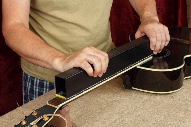 Guitar repair and service Worker grinds black guitar neck frets