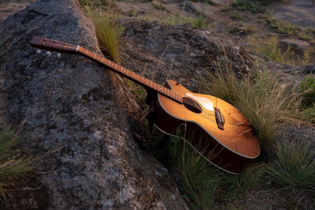 ロック上のギター。日没時のアコースティックギター屋外ギター、音楽の背景のコンセプト。楽器