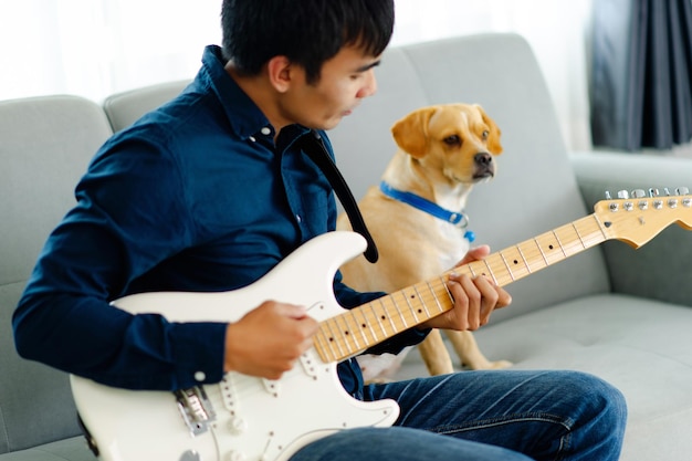 Гитарист играет на гитаре дома на диване Практикует гитару дома Расслабляется, играя на струнных инструментах