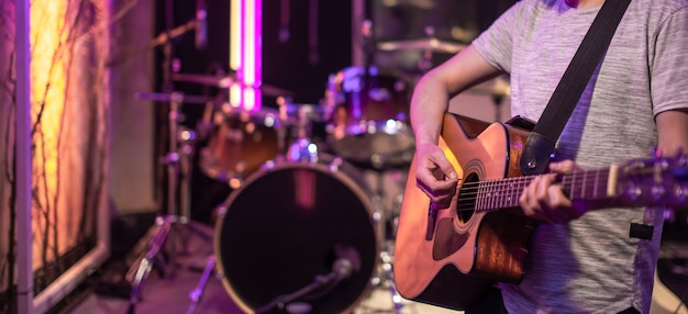 Guitarist playing in room for musicians rehearsals, with a drum kit in the table. The concept of musical creativity and show business.