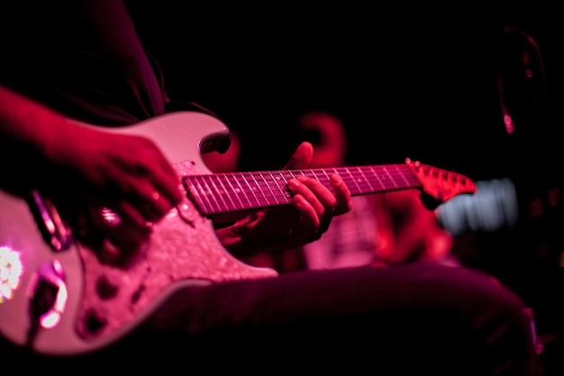 guitarist plays the electric guitar, close-up of the guitar and hands, red lighting