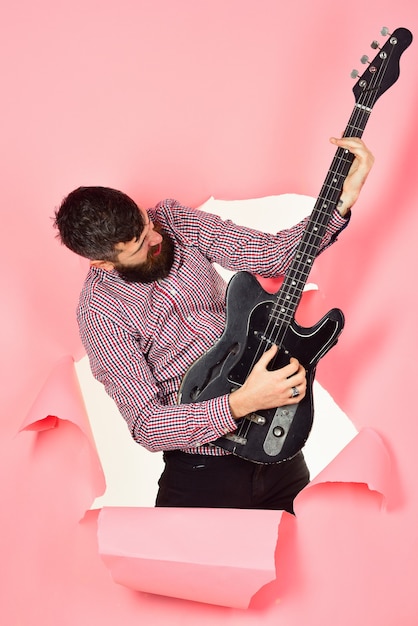 Guitarist through hole in pink paper hold guitar in hand\
bearded man guitarist with electric guitar