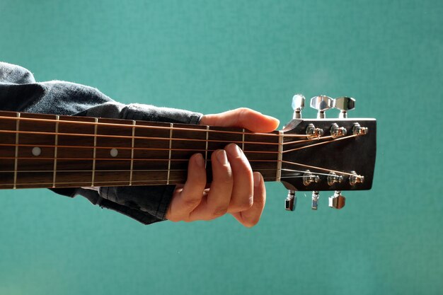 Photo guitars neck in musician hands on blue background close up