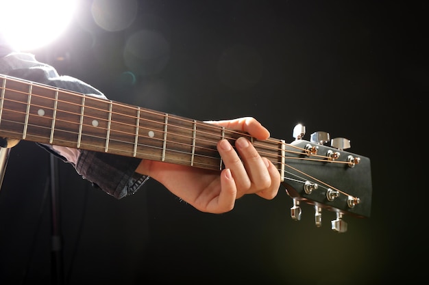 Guitars neck in musician hands on dark background close up