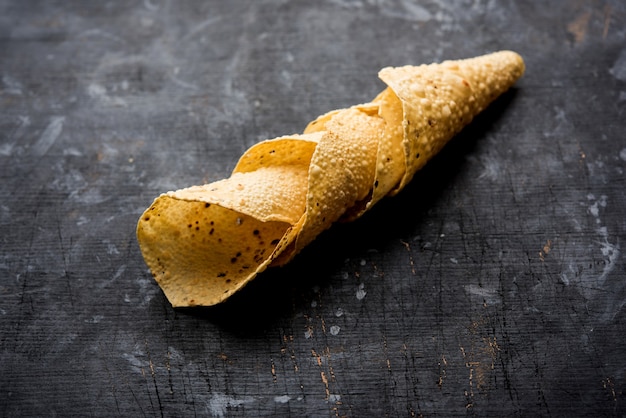 Gujarati papad of papadum in rauwe gedroogde vorm met geroosterde kegel, rol en platte variant