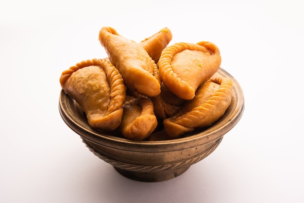 Gujiya 또는 gujia 또는 karanji. 홀리와 디 왈리 축제 기간에 만든 달콤한 만두를 접시에 담았습니다.