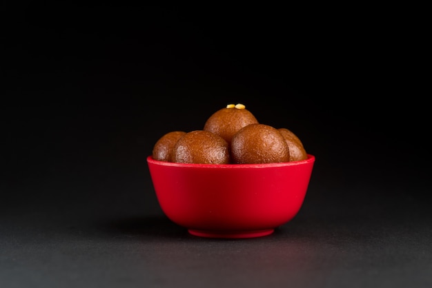 검은 바탕에 그릇에 Gulab Jamun입니다. 인도 디저트 또는 달콤한 요리.