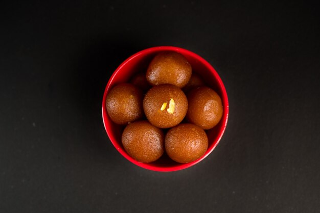 검은 바탕에 그릇에 Gulab Jamun입니다. 인도 디저트 또는 달콤한 요리.