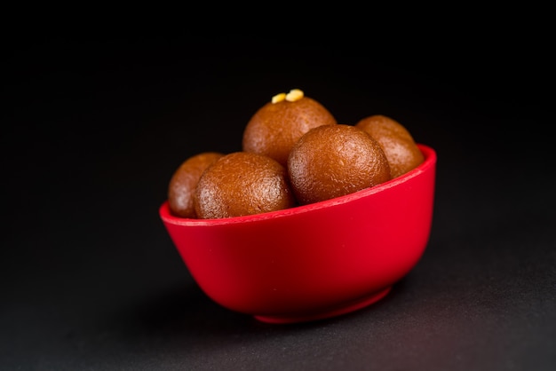 Gulab Jamun in bowl on black. Indian Dessert or Sweet Dish.