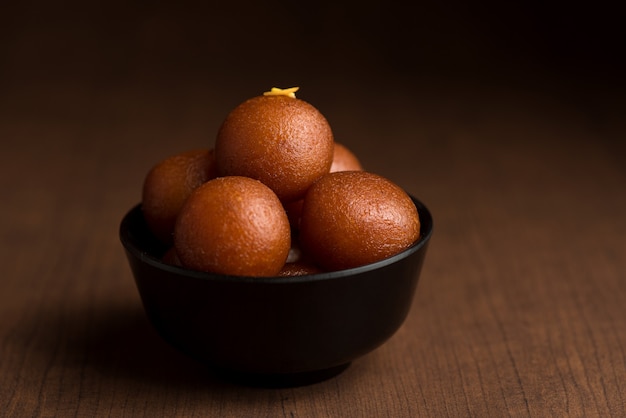 Gulab Jamun in kom op houten achtergrond.