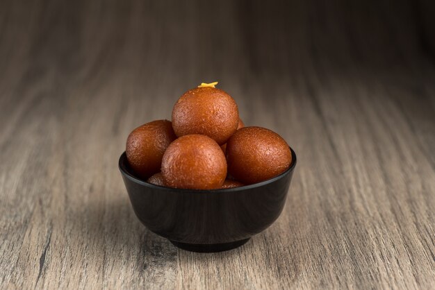 Gulab Jamun in kom op houten achtergrond.