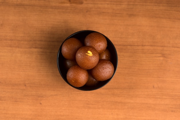 Gulab Jamun in kom op houten achtergrond.