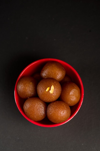 Gulab Jamun in kom op zwart. Indiase dessert of zoete schotel.