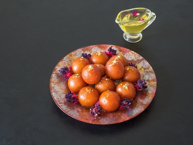 Gulab Jamun - Traditional Indian sweets on a black table.