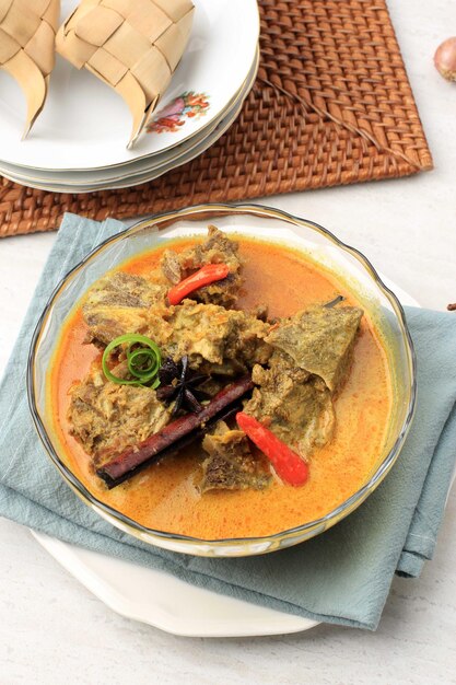 GULAI SAPI Gulai Sapi is Beef Curry, typisch traditioneel voedsel uit Padang, West Sumatera, Indonesië. Geserveerd aan tafel met Bowl en Ketupat Lebaran. Menu voor Eid al Adha (Idul Adha)