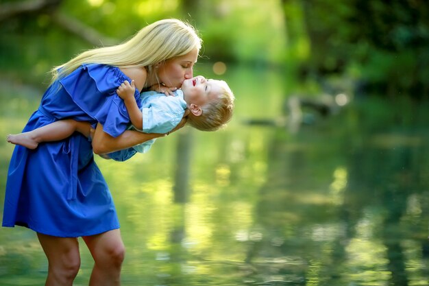 The gules family along the river in the woods with tall trees during the summer holidays