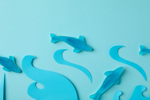 Photo gummy candies in the form of whale and decorative waves on blue background.