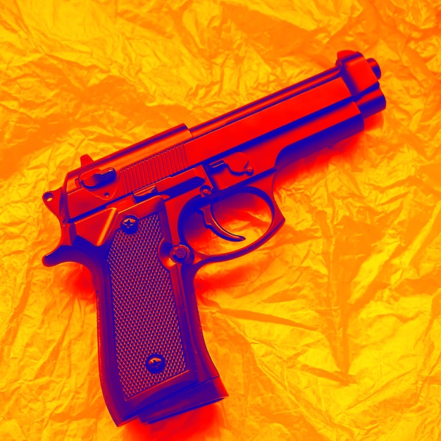 オレンジ色の背景に横たわっている銃。武器の合法化。犯罪の概念。