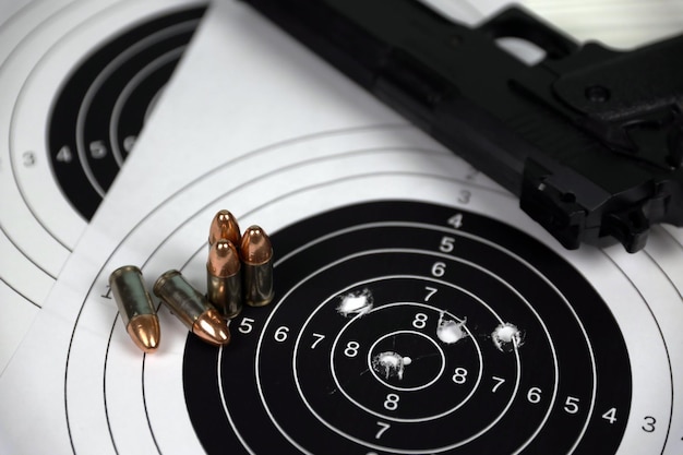 Gun and many bullets shooting targets on white table in\
shooting range polygon training for aiming and shooting