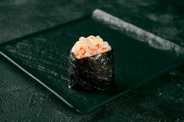 Gunkan maki sushi with salmon and spicy sauce on a black board with ginger and wasabi. Japanese kitchen. Food delivery. Black background