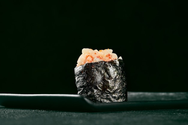 Gunkan maki sushi with salmon and spicy sauce on a black board with ginger and wasabi. Japanese kitchen. Food delivery. Black background