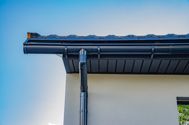 Photo gutter with downpipe on the roof of a house.