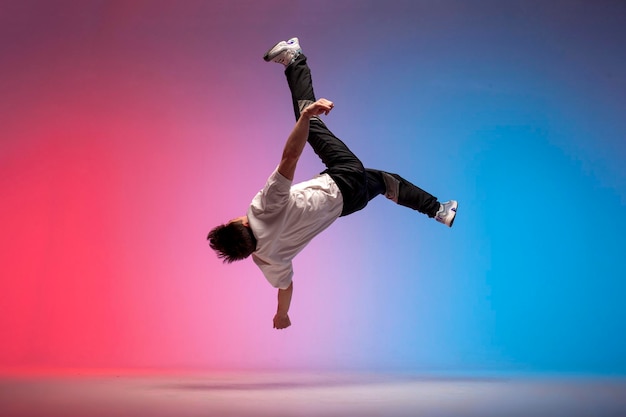 사진 새로운 조명 속에서 등 살을 찌우는 남자 곡예사 남성 댄서가 점프하고 공중으로 떨어집니다.