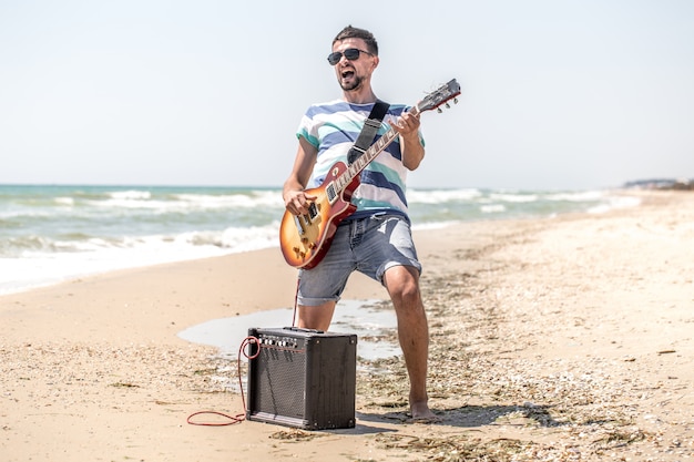 Il ragazzo sulla spiaggia con strumenti musicali