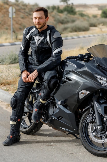 Guy biker in leather jacket looking at the camera sitting on motorcycle Selective focus